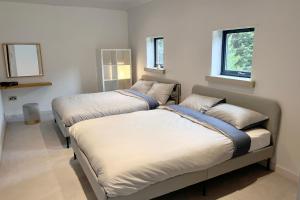 two beds in a room with two windows at One Park Lane in Southwell