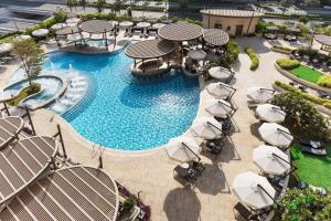 una vista aérea de una piscina con sillas y sombrillas en Hilton Doha The Pearl en Doha