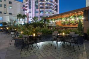 a patio with tables and chairs and a building at Hilton Doha The Pearl in Doha