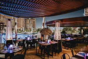 a restaurant with tables and chairs and a pool at Hilton Doha The Pearl in Doha