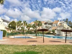 a resort with a swimming pool and umbrellas at Beautiful apartment with pools, playground and paddle tennis - Family friendly and near Vithas Hospital - Free parking in garage in Benalmádena