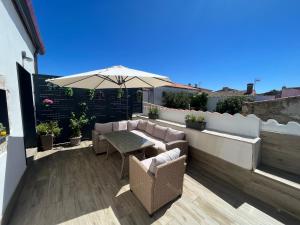 um pátio com um guarda-sol, uma mesa e cadeiras em Apartments BICO DE RODAS a Rural Luxury em Torrequemada