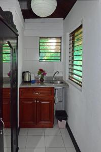 a kitchen with a sink and two windows at Firefly Beach Cottages in Negril