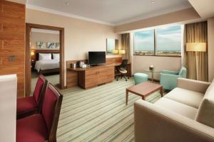 ein Hotelzimmer mit einem Bett und einem Wohnzimmer in der Unterkunft Hilton Garden Inn Al Jubail in Al-Dschubail