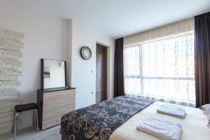 1 dormitorio con 1 cama, vestidor y ventana en La Mer Luxury Apartments, en Golden Sands