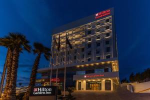 a hotel with palm trees in front of a building at Hilton Garden Inn Casablanca Sud in Casablanca