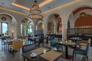 a restaurant with tables and chairs and a chandelier at Hilton Tangier Al Houara Resort & Spa in Al Houara