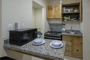 a kitchen with a microwave and a counter with plates at Luxury, cozy apartment Malecon / 3 min Downtown in Santo Domingo