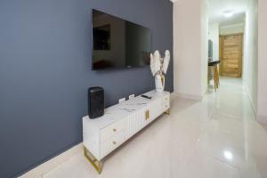 a living room with a white dresser with a tv on the wall at Luxury, cozy apartment Malecon / 3 min Downtown in Santo Domingo