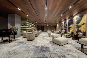uma sala de espera com cadeiras brancas e um piano de cauda em DoubleTree by Hilton Adana em Adana