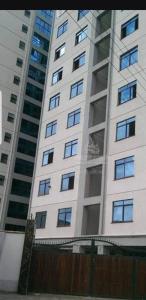 un edificio alto de color blanco con muchas ventanas en JVhomestudios-Ndemi gardens apartments en Nairobi