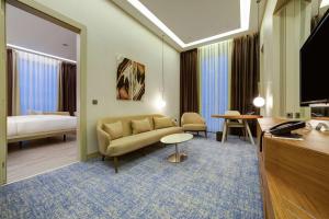 um quarto de hotel com um sofá e uma cama em DoubleTree by Hilton Adana em Adana