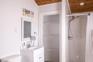a white bathroom with a shower and a sink at Cozy Cabin near Ark! Adam and Eve's Retreat in Williamstown