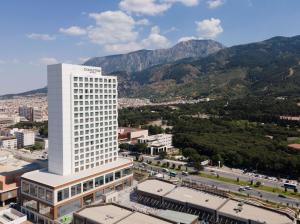 马尼萨DoubleTree by Hilton Manisa的一座高大的白色建筑,背景是群山