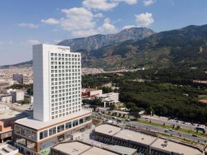 a tall white building with mountains in the background at DoubleTree by Hilton Manisa in Manisa