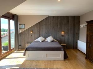 Un dormitorio con una cama con una pared de madera. en La Ferme Des Eglantines, en Nivelles