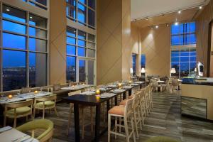 un restaurante con mesas, sillas y ventanas grandes en Hilton Garden Inn Al Khobar en Al Khobar