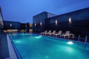 a large swimming pool with chairs and a building at Hilton Garden Inn Al Khobar in Al Khobar