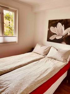 two beds in a bedroom with a flower painting on the wall at Bakklandets Perle 3-roms in Trondheim