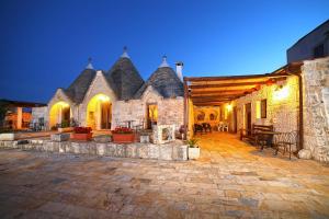 - un grand bâtiment en pierre avec une terrasse la nuit dans l'établissement B&B Salita Delle Pere, à Alberobello