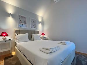a bedroom with a large white bed with towels on it at Nomads Lux - 2BDR Almada Private Porto in Porto
