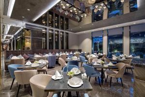um restaurante com mesas, cadeiras e janelas em DoubleTree by Hilton Istanbul - Piyalepasa em Istambul