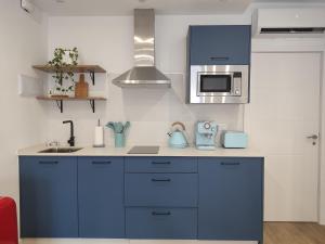 - une cuisine avec des placards bleus et un four micro-ondes dans l'établissement Apartamento Inés y Manolo, à Cordoue