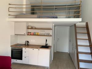 a small kitchen with white cabinets and a loft bed at Sunny studio apartment Chiara in Tivat
