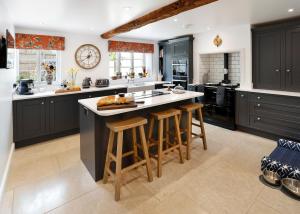 a large kitchen with black cabinets and bar stools at The Old School House in Evesham