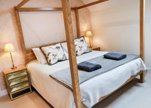 a bedroom with a four poster bed with two pillows at The Old School House in Evesham