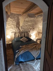 een slaapkamer met een bed in een stenen muur bij Gite des Perreyeurs - maison troglodyte avec vue sur Loire in Montsoreau