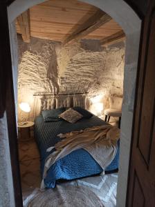 - une chambre avec un lit dans un mur en pierre dans l'établissement Gite des Perreyeurs - maison troglodyte avec vue sur Loire, à Montsoreau