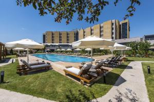 una piscina con tumbonas y sombrillas en DoubleTree By Hilton Avanos Cappadocia, en Avanos