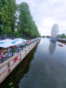 Un río con un muelle con mesas y un bote. en D-Mansard, Free parking, Self-Check-In, en Klaipėda