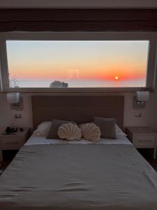 サンタ・マリア・ディ・カステッラバーテにあるMiramare Castellabate Resortのベッドルーム1室(ベッド1台、夕日を望む窓付)
