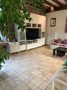 a living room with a television and a tiled floor at Fermette nature chez le particulier in Courgenay