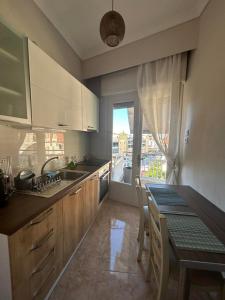 eine Küche mit einem Tisch, einem Waschbecken und einem Fenster in der Unterkunft Nektar Suites in Kavala