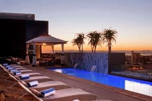 a pool on the rooftop of a building with palm trees at Hilton Windhoek in Windhoek