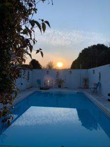 a blue swimming pool with the sunset in the background at Silverspring Farm En suite in Constantine