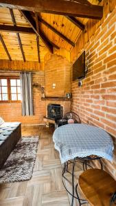 ein Wohnzimmer mit einem Tisch und einer Ziegelwand in der Unterkunft Recanto de Minas in Monte Verde