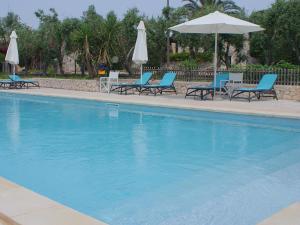 una piscina con sedie blu e ombrelloni di Residence Conchiglia San Giovanni a Santa Cesarea Terme