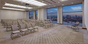 Doubletree by Hilton Istanbul Umraniye في إسطنبول: قاعة المؤتمرات مع الكراسي والطاولات والنوافذ