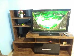 a flat screen tv sitting on a wooden entertainment center at Quartos Morumbi in Foz do Iguaçu