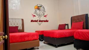 um quarto com duas camas com um pássaro na parede em Hotel Garuda em Rambah
