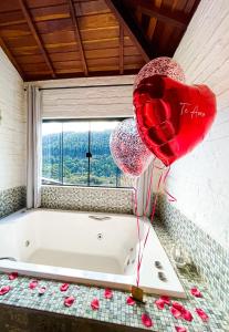 eine Badewanne mit zwei roten Herzen und Ballons in der Unterkunft Recanto de Minas in Monte Verde