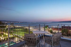 balcón con mesa, sillas y vistas al océano en Doubletree By Hilton Canakkale, en Canakkale