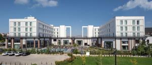 un grand bâtiment blanc avec des voitures garées dans un parking dans l'établissement Doubletree By Hilton Canakkale, à Çanakkale