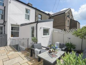 un patio con mesa, sillas y una valla en Maelgwyn, en Criccieth