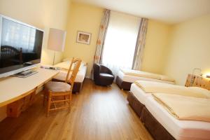 a hotel room with two beds and a desk with a computer at Ambiente Hotel Freieck in Chur