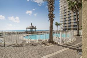 a fence with a pool and the ocean in the background at Summer House 103A by Vacation Homes Collection in Orange Beach